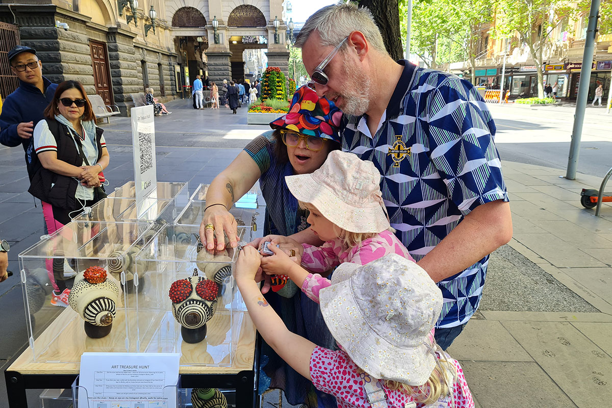 Family doing treasure hunt activity involving artworks in transparent case on city street