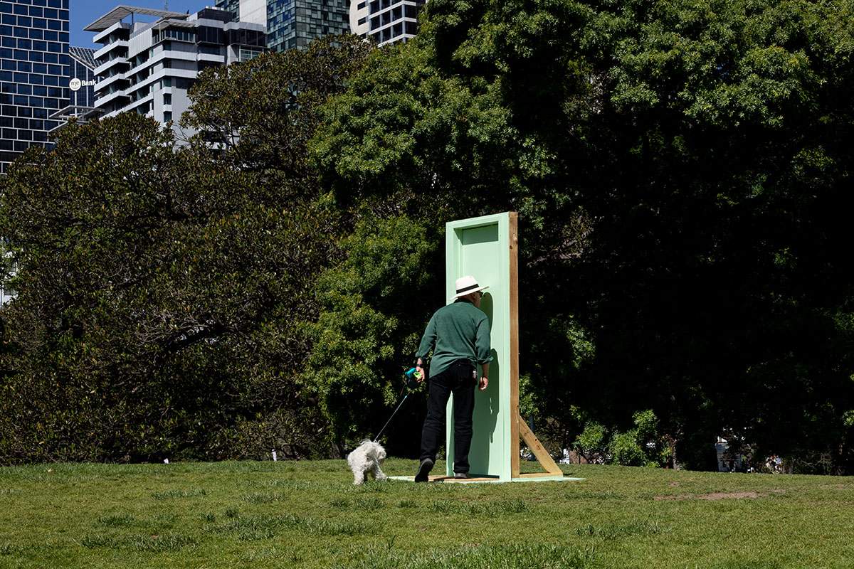 Man with dog closely examining freestanding wooden door in city park