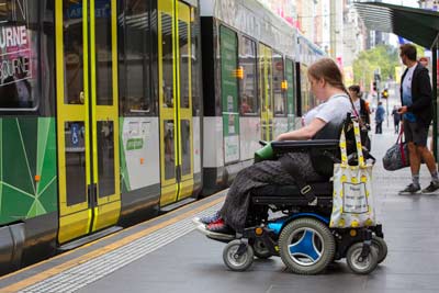 Person in a wheelchair at an accessible tram stop in the city
