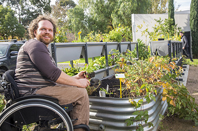 Man in wheelchair next to outdoor garden plot