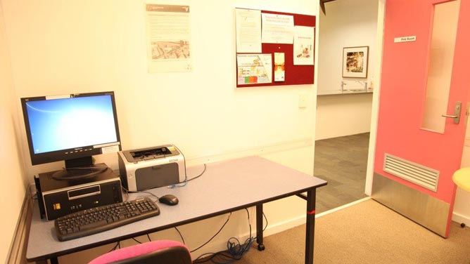 A small room with computer and printer on a desk