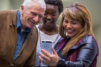 Three people looking at a phone.