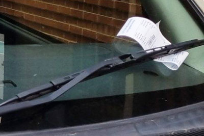A parking fine on a car windscreen.