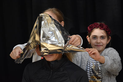 Two children put some foil on a woman's head.