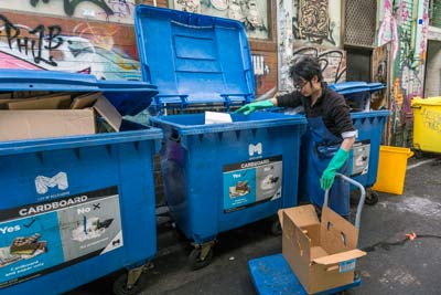 Man putting cardboard into a recycling bin