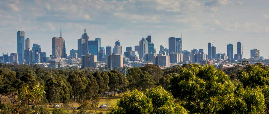 Panoramic view of Melbourne CBD buildings, with parklands in the foreground
